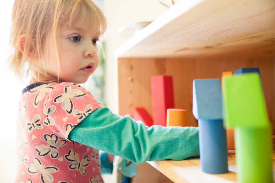 Toddler girl playing with blocks on shelf