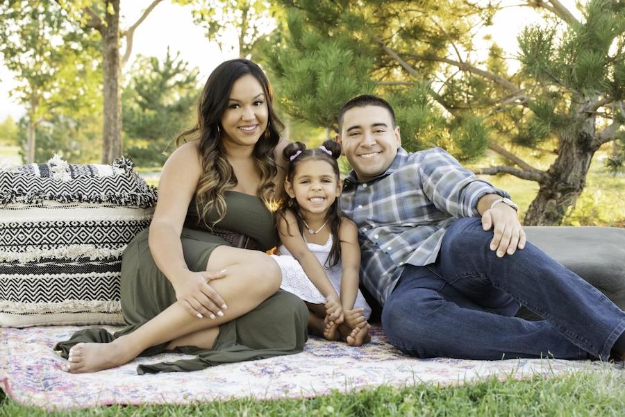 Family of mother, father and little girl sitting on grass