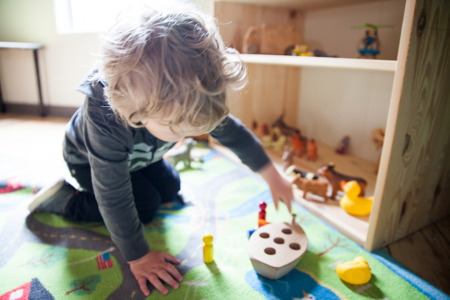 Young child on colorful carpet playing with toys