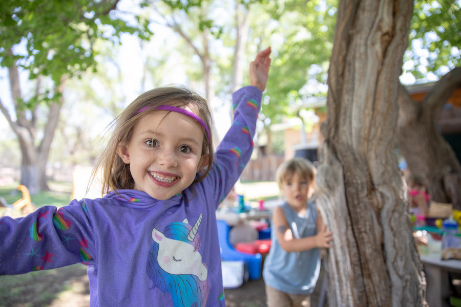 Little girl standing outside with her hands in the air