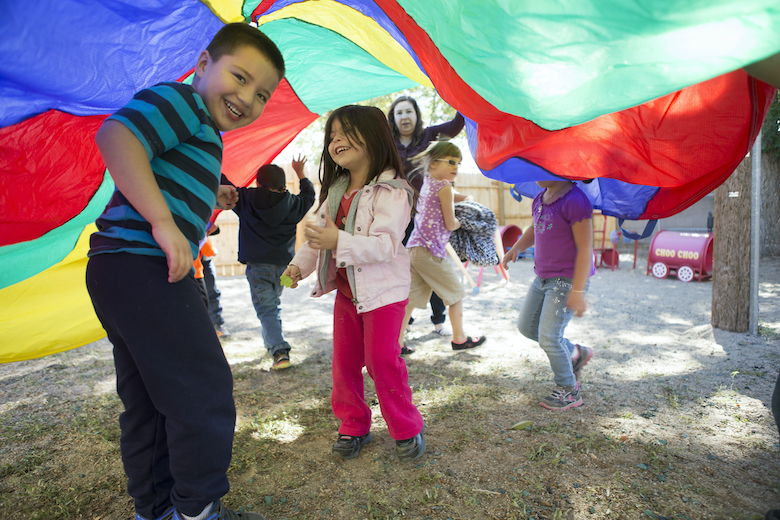 Kids playing under multi-colored tarp outside