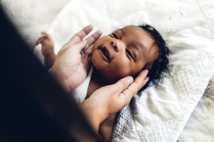 Mothers hands around baby's face