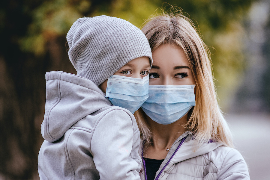 a girl with a child stands on the road in a protective medical mask. Dense smog on the streets. Epidemic of the flu