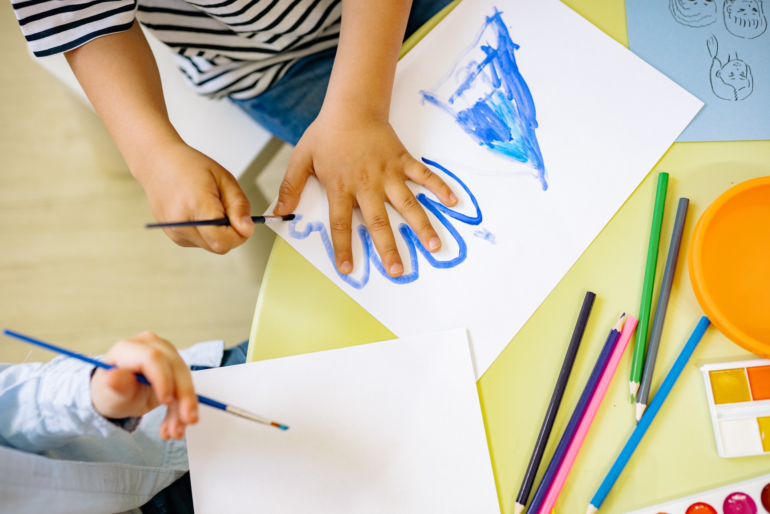 Two kids tracing their hands with paint