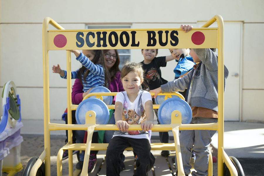 Kids sitting on school bus play structure outside