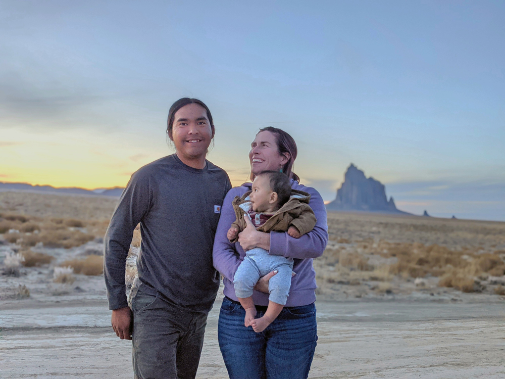 Mother and father standing outside with baby in desert background