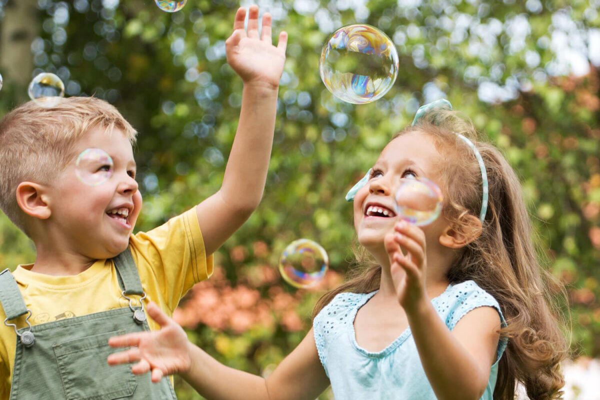 2 children playing outside blowing bubbles