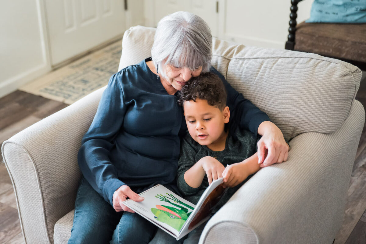 an adult and child reading a book together on a couch