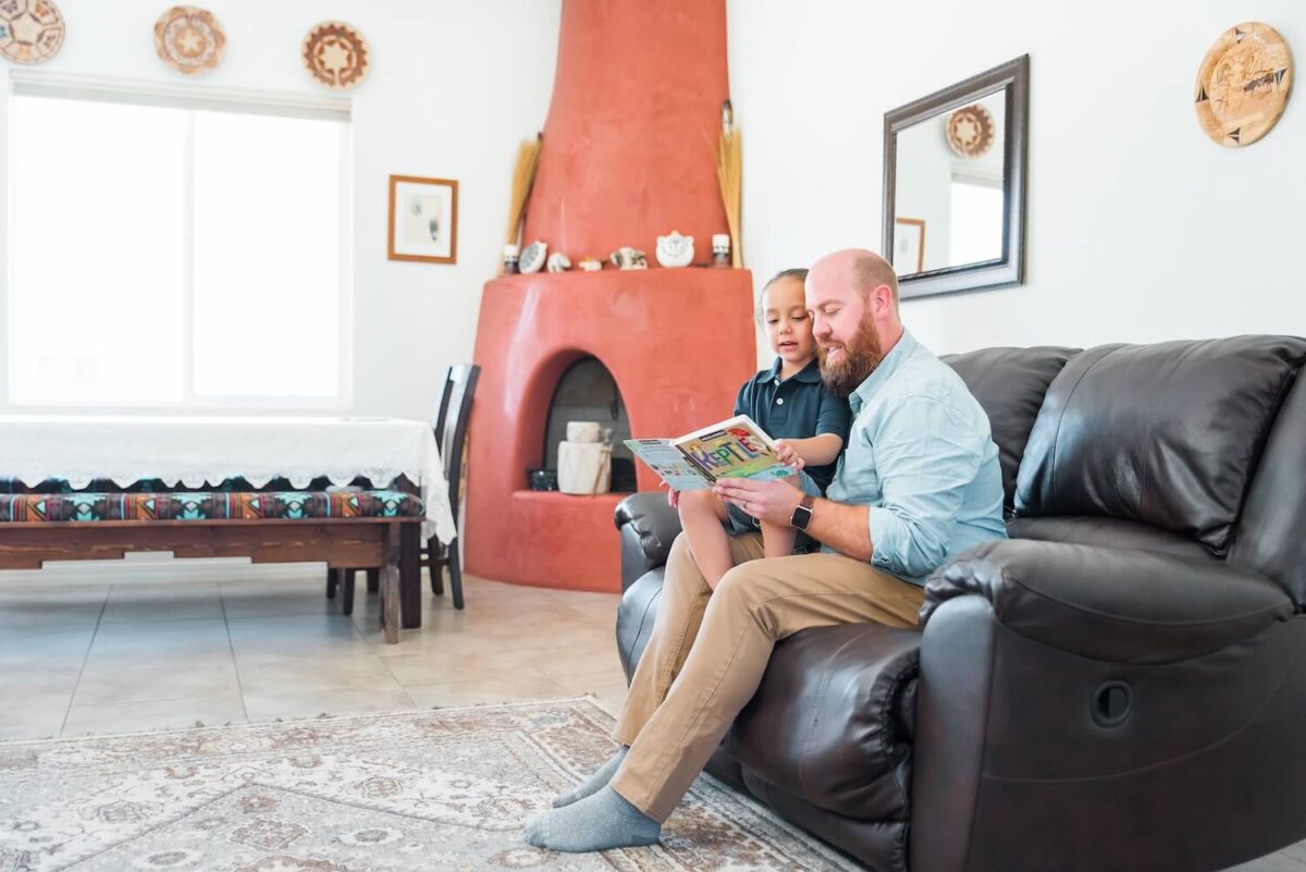 Father and son reading a book in the home's living room.
